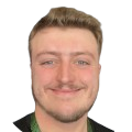 A picture of Jack Ryan, Sage. He is smiling at the camera wearing a black t-shirt and a green lanyard.